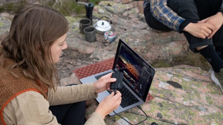 Wyprawa w góry. Turystyka ładująca telefon za pomocą laptopa